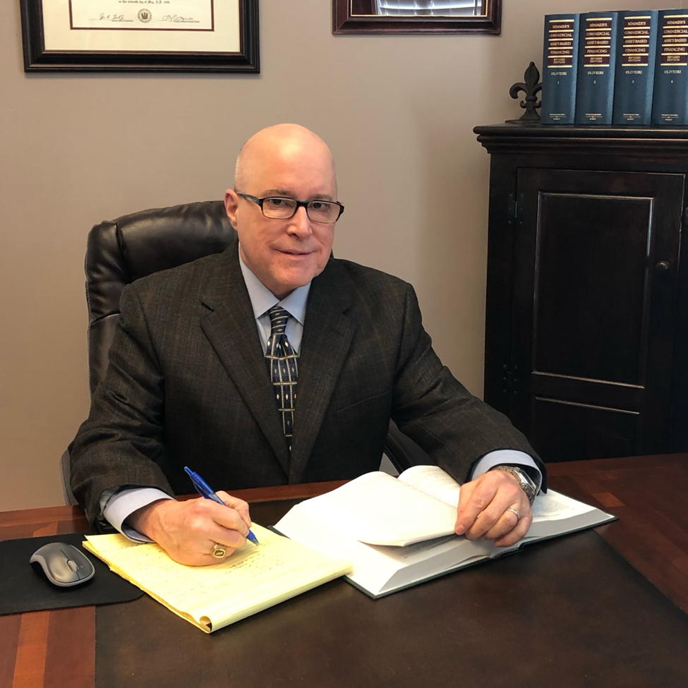 Professional man in a suit writing at a desk in an office.