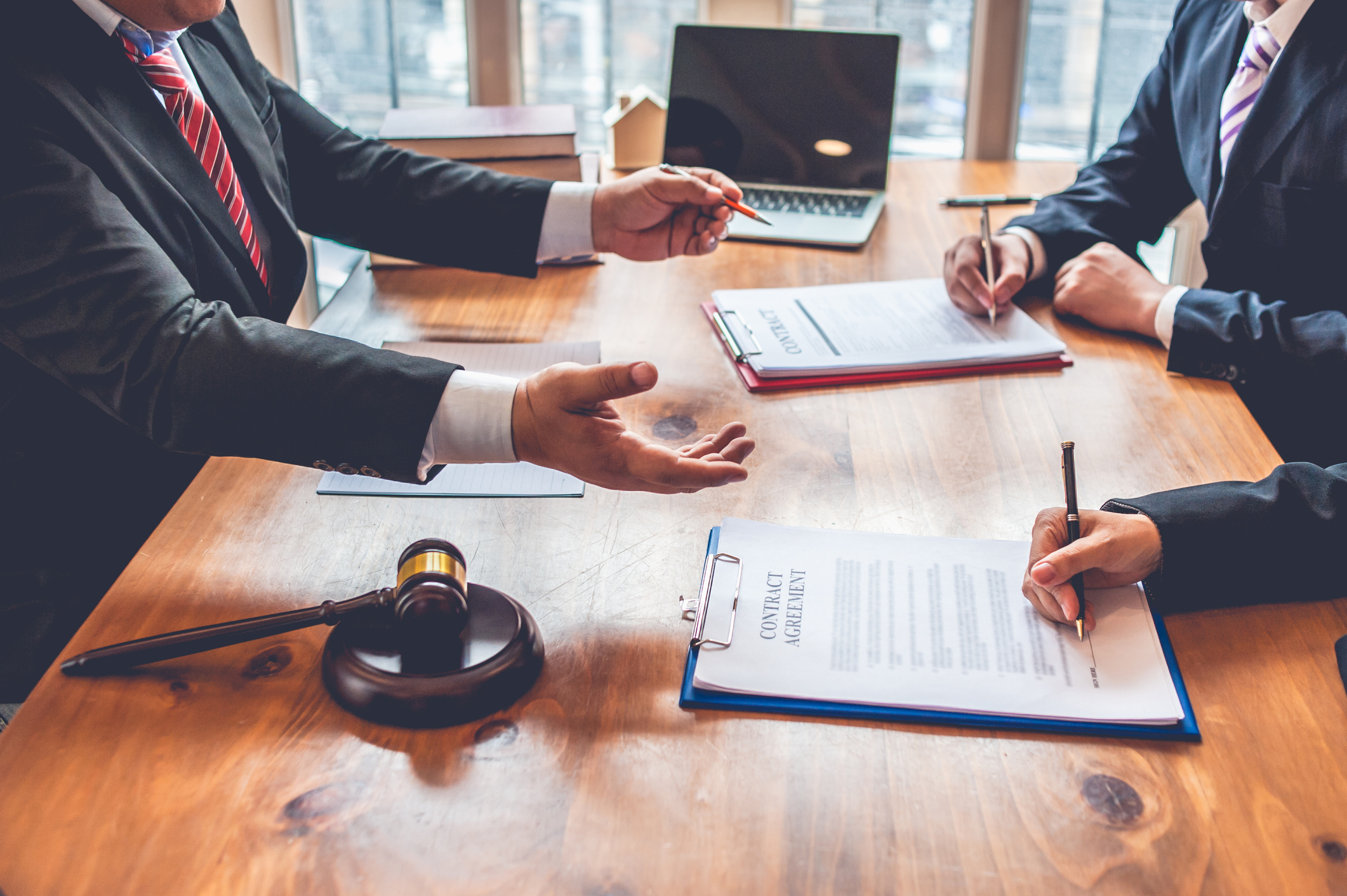 Legal professionals discussing documents at a wooden table with a gavel present.