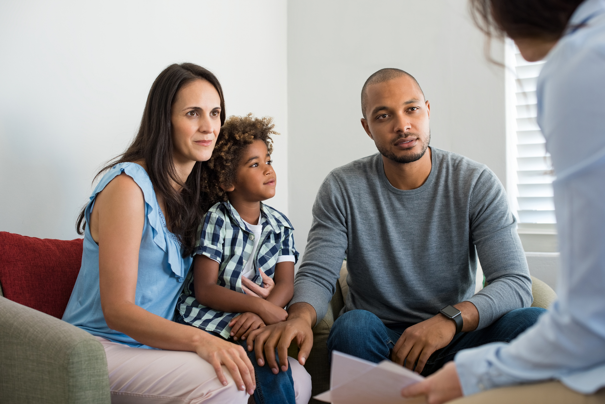 A family of three sitting together, looking attentive.