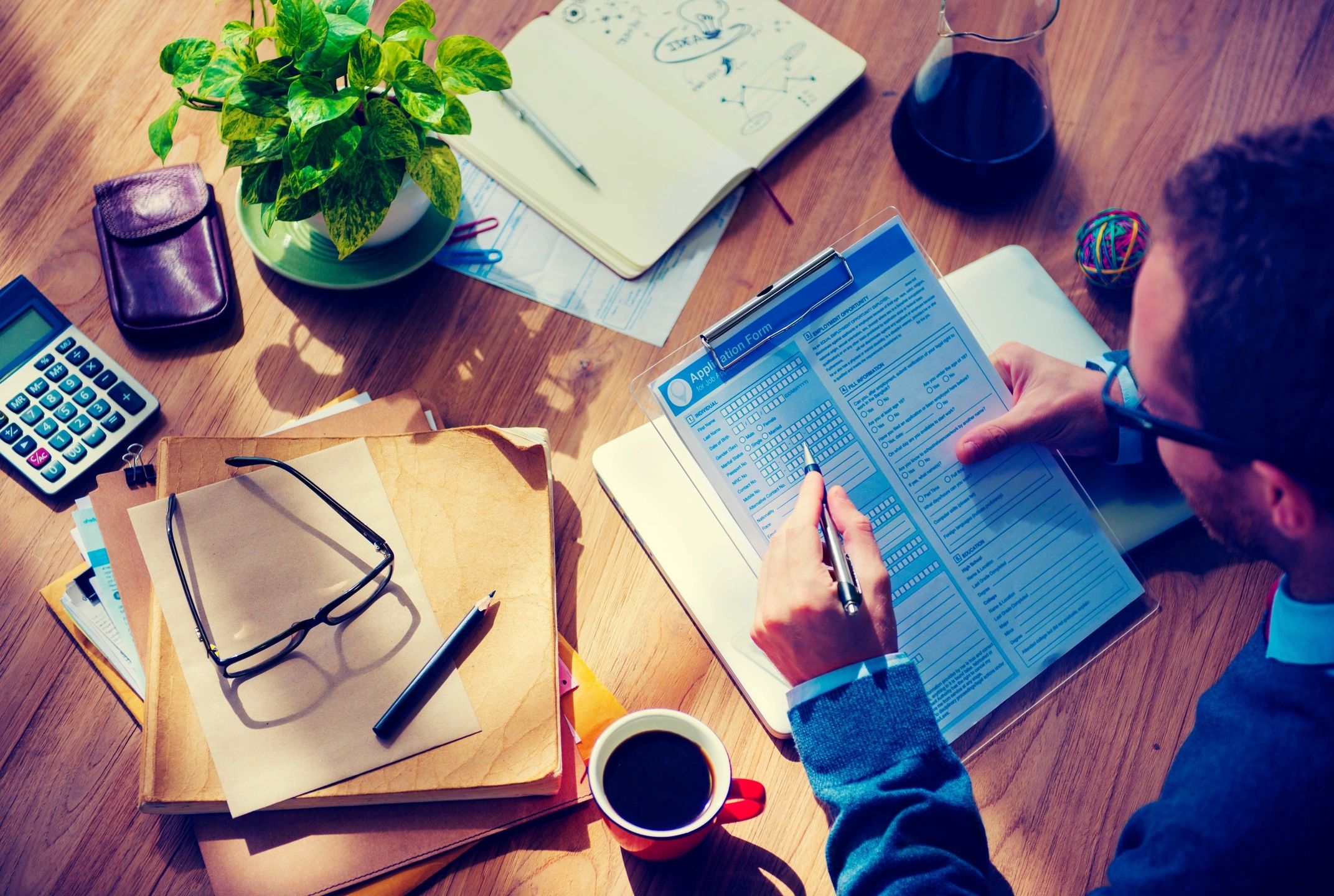 Person reviewing documents with coffee and glasses on the desk.