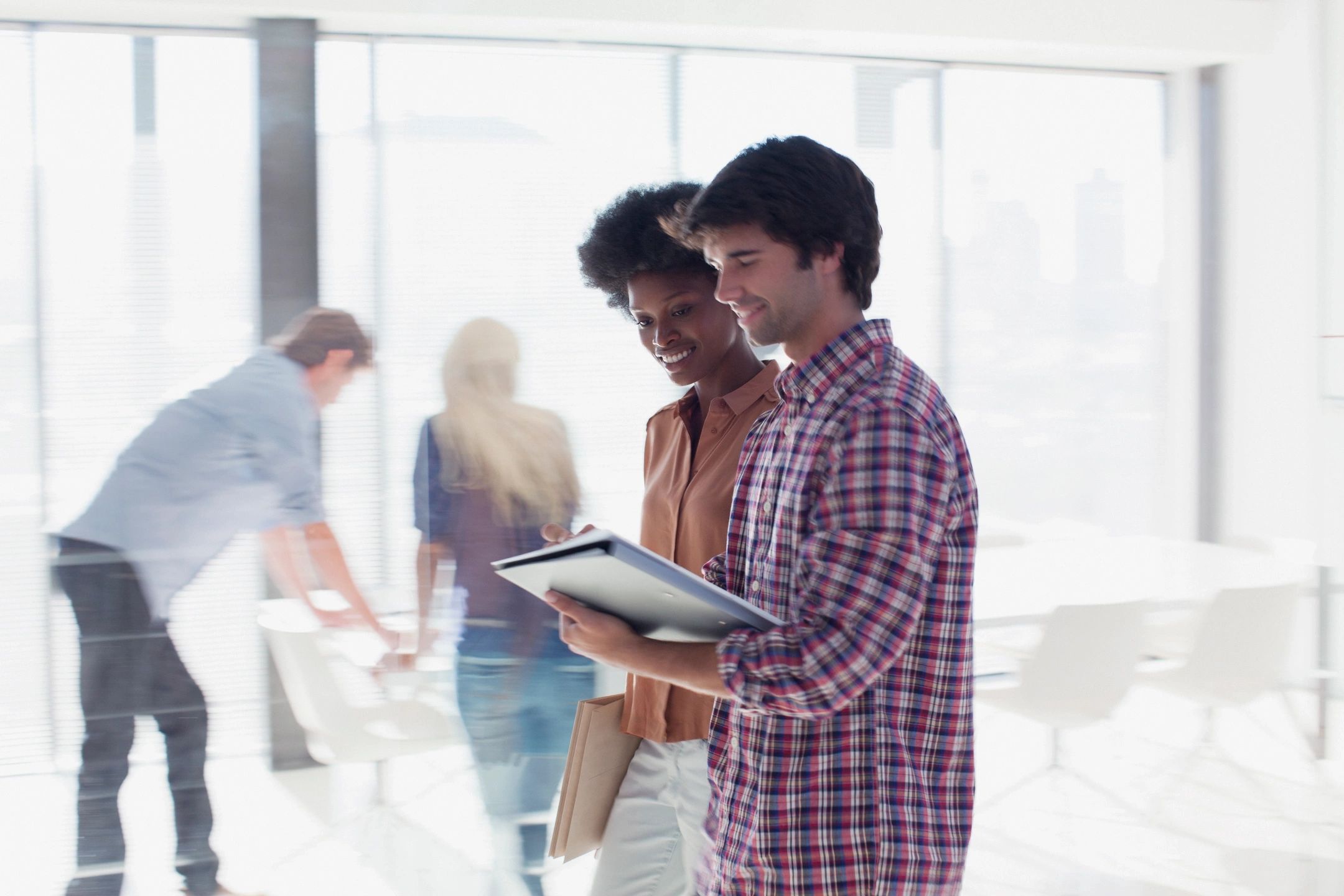 Two young men discussing work on a tablet in a modern office.