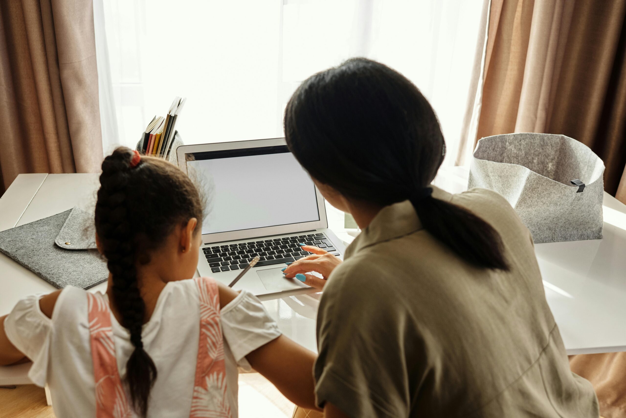 A woman and a girl working on a laptop together.