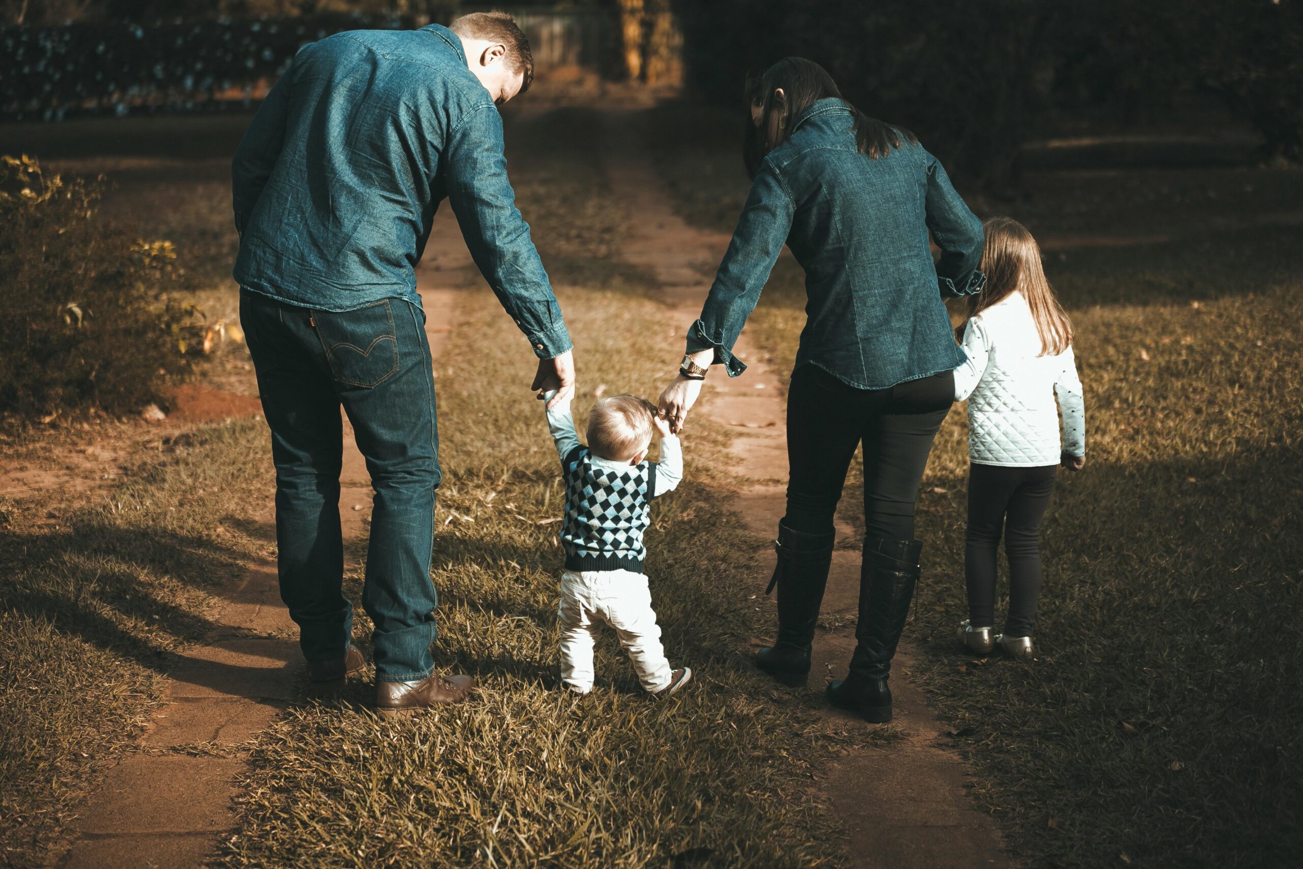 Parents walking with their children holding hands at dusk.