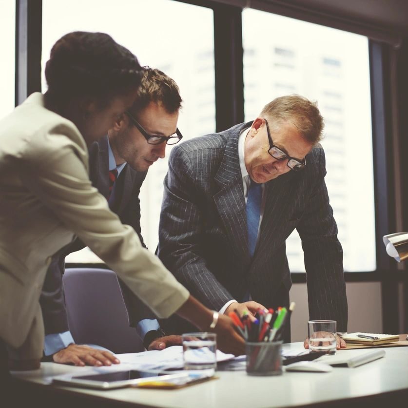 Three professionals collaborating intensely over documents in an office.