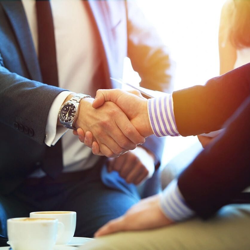Two people shaking hands in a business setting.