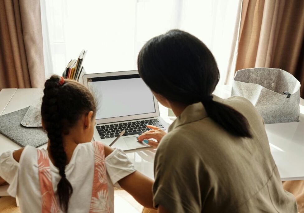 A woman and a girl working on a laptop together.