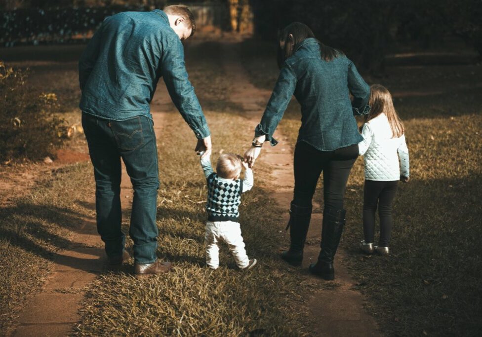 Parents walking with their children holding hands at dusk.