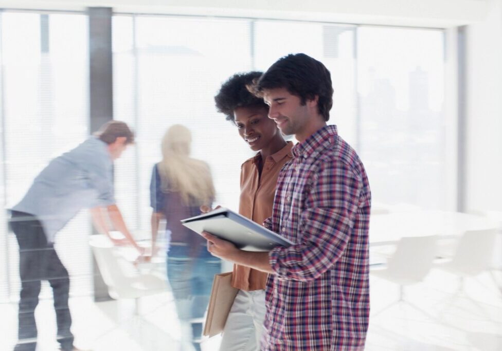 Two young men discussing work on a tablet in a modern office.